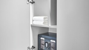 A white cabinet with shelves, one of which holds rolled towels and two green cacti. - Hanomag Quartier (Hannover)