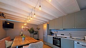 A modern kitchen with a wooden dining table, grey cabinets, and a built-in oven. - Hanomag Quartier (Hannover)