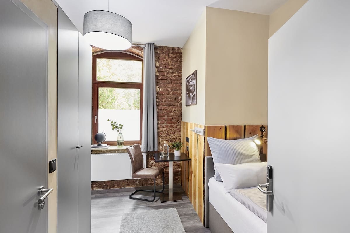 A modern room with a brick wall, a wooden headboard, a desk with a chair, and a bed with a headboard.