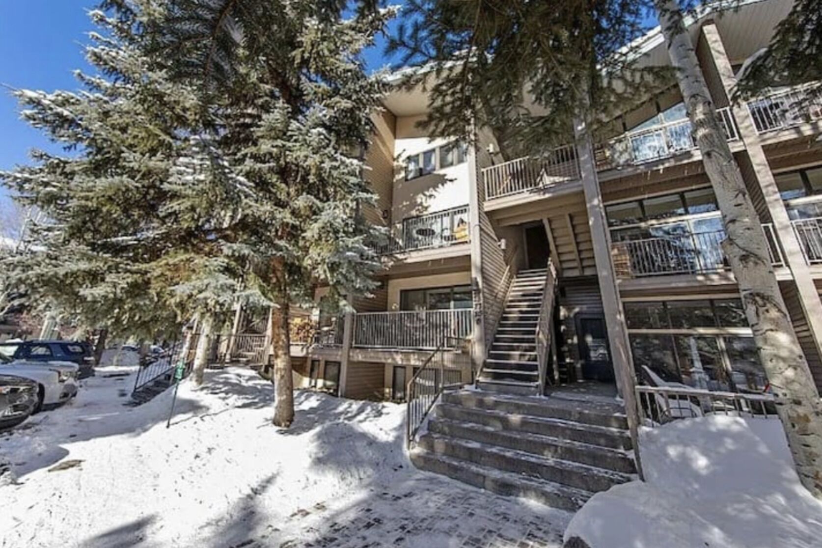 A multi-story building with a staircase leading to the entrance, surrounded by snow-covered ground and trees.