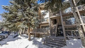 A multi-story building with a staircase leading to the entrance, surrounded by snow-covered ground and trees.