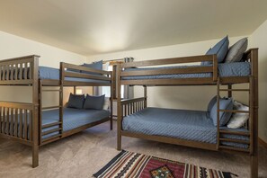 Une chambre avec des lits superposés, un tapis à motifs et une fenêtre avec des rideaux.