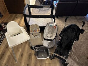 A room with a crib, a stroller, a baby seat, and a high chair. - BC/Avon Mtn Gem-3BR/Pool/Hot Tub/Ski Shuttle/Sauna/Gondola Walk! (Avon)