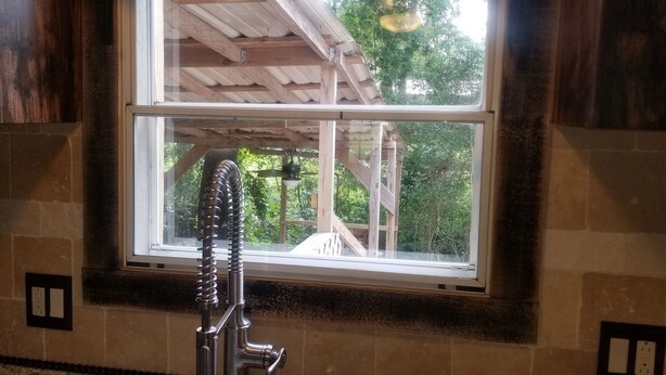 A bathroom with a window overlooking a wooden deck and greenery. - Clean and Cozy Creekside Home (Conroe)