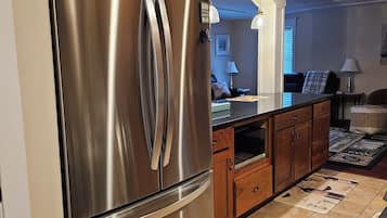Une cuisine moderne dotée d’appareils électroménagers en acier inoxydable, de meubles en bois et d’un sol carrelé.
