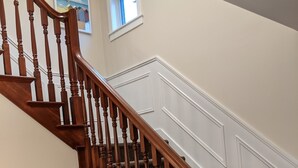 A wooden staircase with a carpeted landing and a white wall with a small window. - Newly updated,close to downtown and the lake, pet friendly  (Grand Haven)