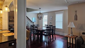 A dining area with a wooden table and chairs, a chandelier, and a staircase leading to another level. - Newly updated,close to downtown and the lake, pet friendly  (Grand Haven)