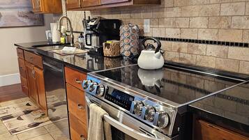 Une cuisine moderne avec des meubles en bois, une cuisinière en acier inoxydable et un dosseret carrelé.