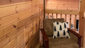 Interior de una cabaña de madera con una zona de estar acogedora, techo de madera y una fotografía de un oso en la pared.