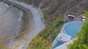 Zona de piscina con jacuzzi, terraza y vistas a la playa.