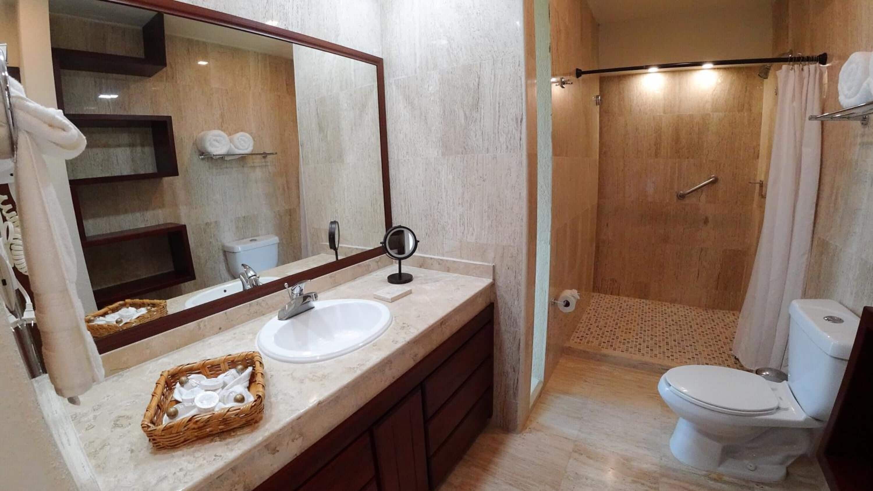 A bathroom with a sink, mirror, and shower.
