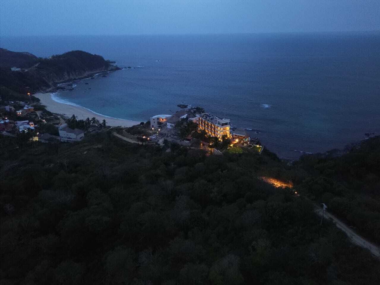 A coastal hotel with a beachfront view, surrounded by dense vegetation.