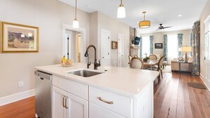 Una cocina moderna con una isla central, pileta de acero inoxidable y muebles de cocina blancos.