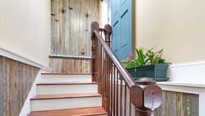 Una escalera de madera con barandilla, paredes blancas y una puerta azul.