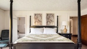 A four-poster bed with a white and green patterned bedspread, a dark wooden headboard, and two abstract wall art pieces above the bed. - A beautiful historic property in Downtown Detroit on the river side! Welcome FC! (Detroit)