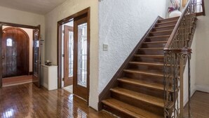 A spacious hallway with wooden flooring, a staircase with ornate metal railings, and a door with a glass window. - A beautiful historic property in Downtown Detroit on the river side! Welcome FC! (Detroit)