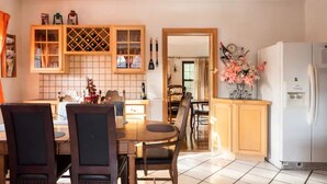 A kitchen with a dining area, featuring a white refrigerator, wooden cabinets, and a tiled backsplash. - A beautiful historic property in Downtown Detroit on the river side! Welcome FC! (Detroit)