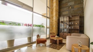 A modern interior with a large glass wall, a stone wall, and a wooden bookshelf. - Best Western Plus Hotel San Diego (Medellín)
