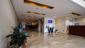 A hotel lobby with a reception desk, a television, a fire extinguisher, and a potted plant. - Best Western Plus Hotel San Diego (Medellín)