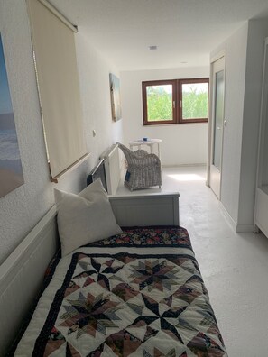 A bedroom with a bed, a window, a chair, and a small table.