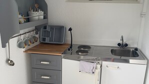 Una cuina compacta amb rentatge, fogó i armaris d'emmagatzematge.