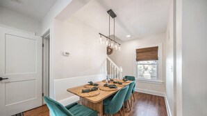 Un coin repas avec une table en bois, des chaises de couleur turquoise et un lustre.
