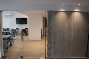 Un espace de bureau moderne doté de cloisons en verre, d’un téléviseur à écran plat et d’un mur décoratif en béton.