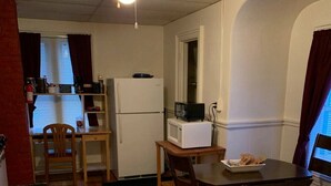 Eine kleine Küche mit Kühlschrank, Mikrowelle und einem Essplatz mit Stühlen.