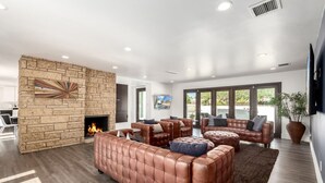 Un salon moderne avec une cheminée en pierre, des canapés en cuir et une grande fenêtre donnant sur l’extérieur.