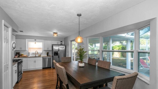 A modern kitchen with white cabinets, stainless steel appliances, and a wooden dining table with chairs.
