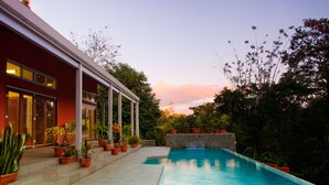 A modern house with a swimming pool, surrounded by potted plants and a garden. - Arenal-Area Jungle Lodge — Pool Access, 5BR/6.5BA, Sleeps 20 (Cabanga)