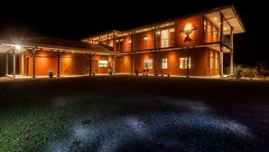 A large, multi-story building with a prominent H&L logo, multiple windows, and a covered entrance area. - Arenal-Area Jungle Lodge — Pool Access, 5BR/6.5BA, Sleeps 20 (Cabanga)