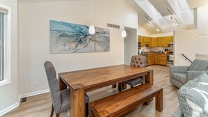 A modern kitchen with wooden cabinets, a dining area with a wooden table and bench, and a gray patterned sofa. - Beautiful home, quiet neighborhood w hot tub. Close to shopping, beach & trails. (Holland)