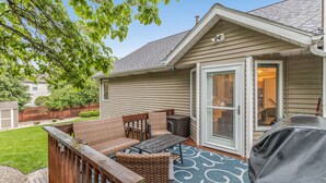 A covered patio with wicker furniture, a grill, and a sliding glass door leading to an interior space. - Beautiful home, quiet neighborhood w hot tub. Close to shopping, beach & trails. (Holland)
