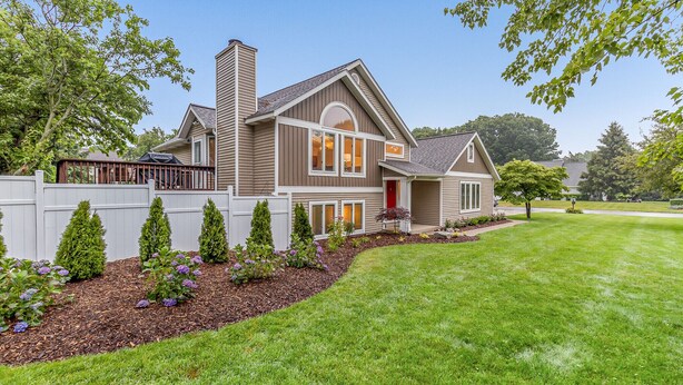 A two-story house with a red door, a covered patio, and a well-maintained lawn. - Beautiful home, quiet neighborhood w hot tub. Close to shopping, beach & trails. (Holland)