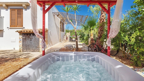 Un jacuzzi bajo una pérgola de madera, con un cielo azul despejado al fondo.