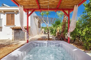 Ein Whirlpool unter einer Holzw pergola mit blauem Himmel im Hintergrund.