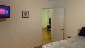 A bedroom with a bed, a television on the wall, and a door leading to another room. - Stocked home close to Yale, in Heart of New Haven (New Haven)