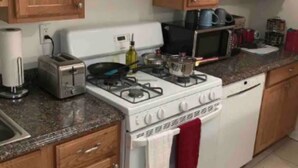 A kitchen with wooden cabinets, a white stove, a microwave, and a toaster. - Stocked home close to Yale, in Heart of New Haven (New Haven)
