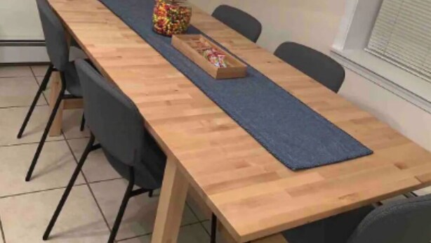 A conference room with a long wooden table, black chairs, a blue runner, a jar of candies, a small box, and a framed artwork on the wall. - Stocked home close to Yale, in Heart of New Haven (New Haven)