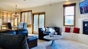 A spacious living room with a fireplace, a dining area, and a kitchen with wooden cabinets.