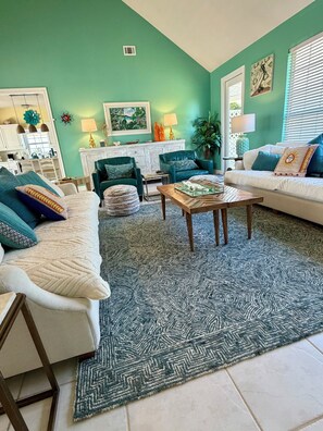 Una sala de estar con sofá, sillón, mesa de centro y alfombra estampada.