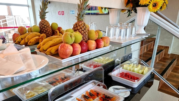 Un bufé con diversas frutas y verduras, entre ellas plátanos, manzanas y piñas.
