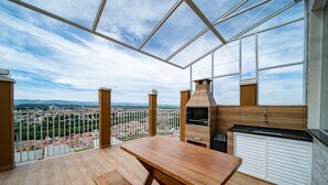 Un balcón amplio con una mesa y banco de madera, con vistas a un paisaje urbano.