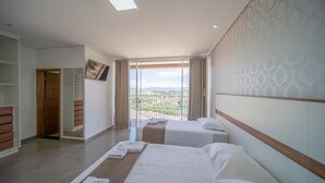 Una habitación de hotel con dos camas, un ventanal con vistas y un armario.