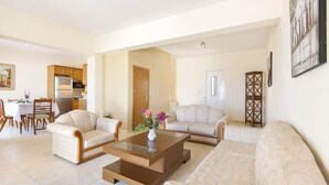 Amplia sala de estar con un conjunto de sofás, una mesa de centro y un comedor con mesa y sillas.