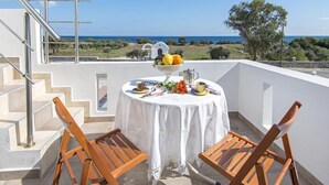 Un balcón con una mesa dispuesta para dos, con vistas a un paisaje pintoresco.