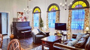 A living room with a piano, sofa, TV, and decorative items. - ★ Church House ★UNIQUE 2bd converted historic Wallace chapel, walk to everything (Wallace)