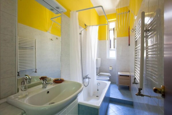 A bathroom with a bathtub, a sink, and a toilet. - Colorful apt in Milano (Milan)