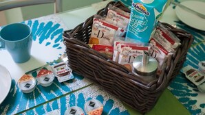 A wicker basket containing various food items and a carton of milk on a table with a blue and white patterned tablecloth. - Colorful apt in Milano (Milan)